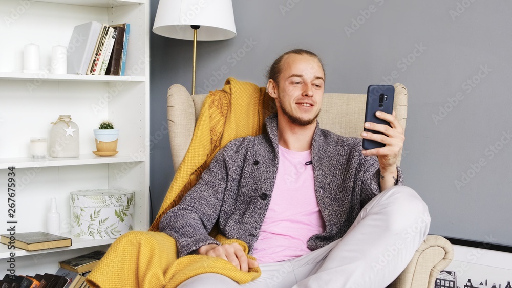 A young man uses Zepeel, looks at the phone. Live. Front-camera