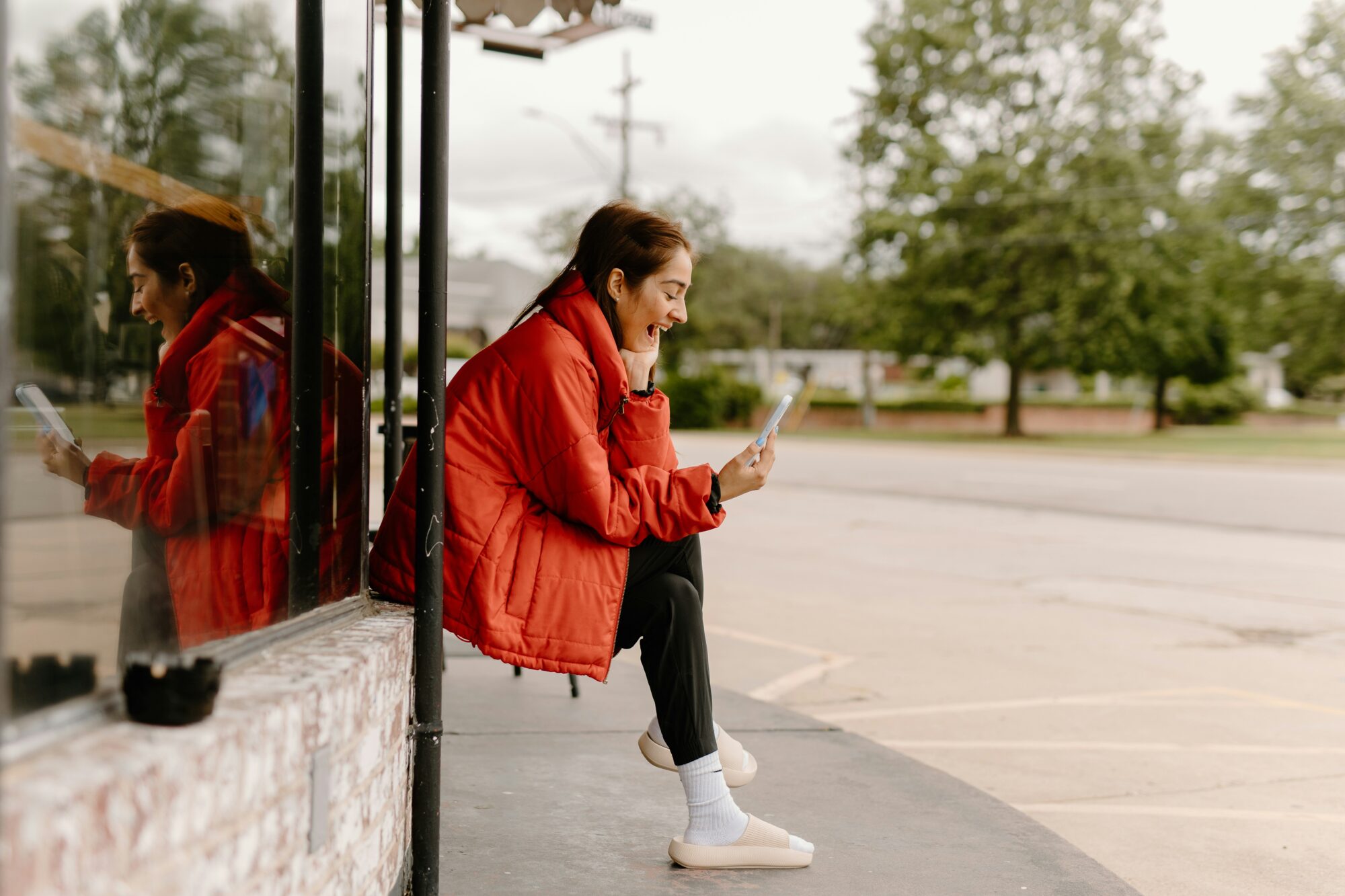 a woman in a red jacket looking at zepeel on her phone