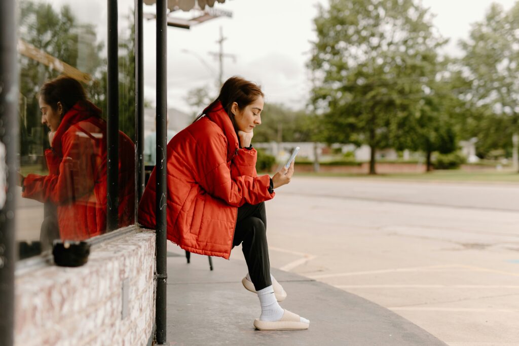 a woman sitting on a bus looking at her zepeel notification