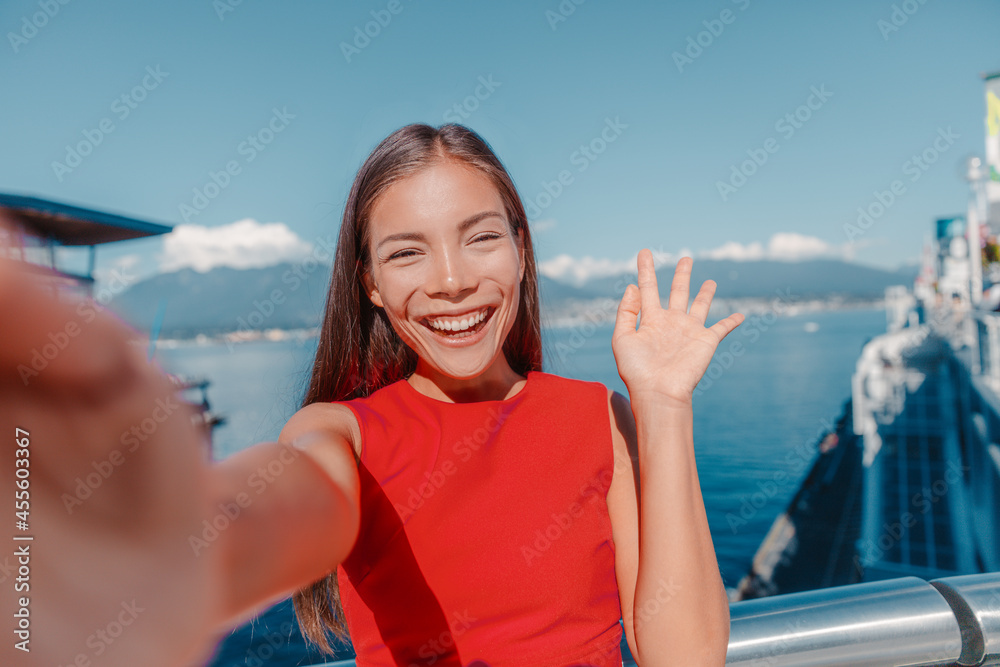 Woman waving hello looking at camera on video call calling for online date on zepeel while walking outside on travel. Coal Harbour, Vancouver, canada.