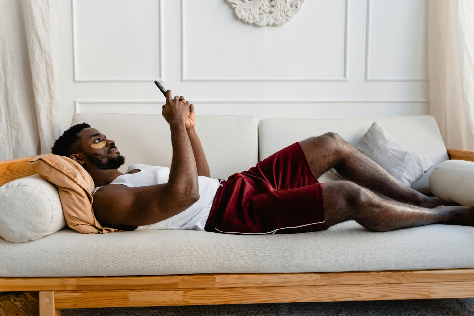 A man wearing an eye mask lying on the couch browsing zepeel singles